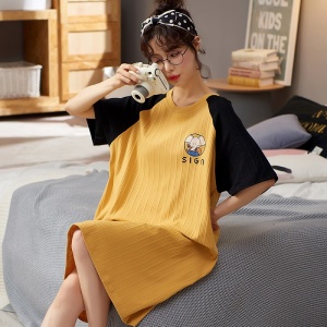 Pyjama d'été robe de nuit à manches courtes jaune et noir pour femmes portée par une femme assise sur un lit dans une maison