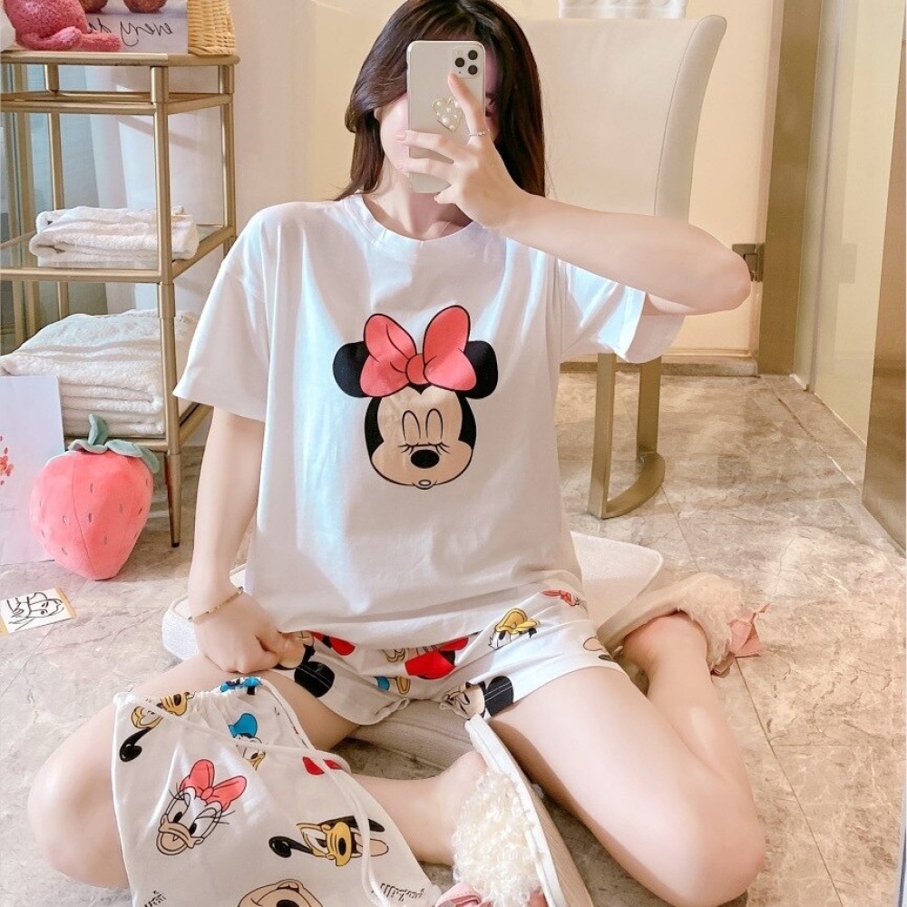 Ensemble pyjama d'été en satin imprimé Minnie Mouse portée par une femme assise sur un lit dans une maison
