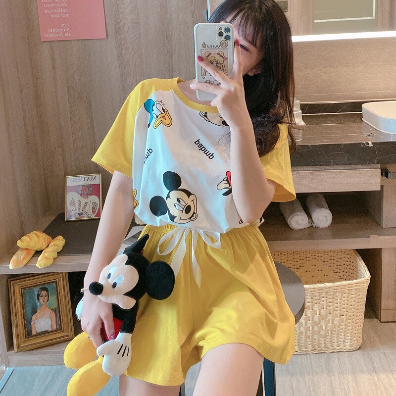 Pyjama d’été imprimé Mickey Donald jaune porté par une femme qui porte une peluche