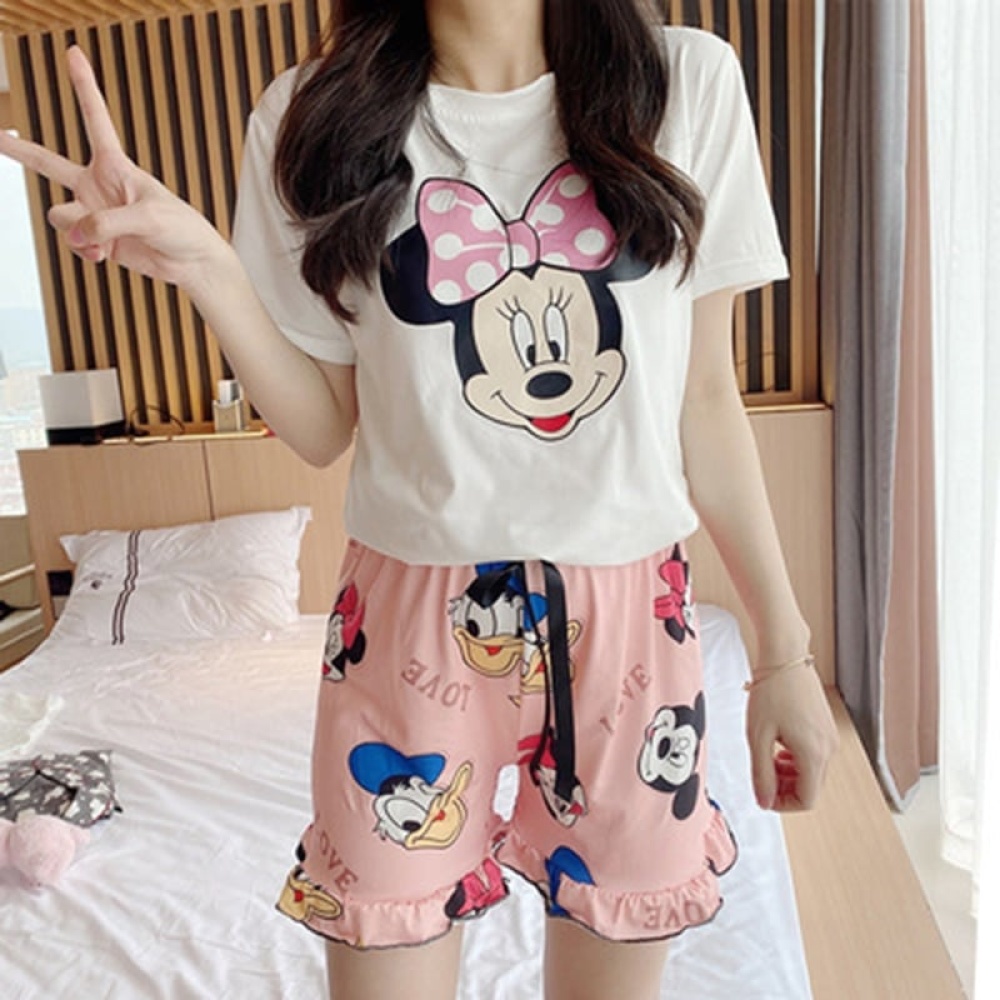 Pyjama d’été imprimé Minnie, Mickey et Donald roses et blanc, portée par une femme dans une maison
