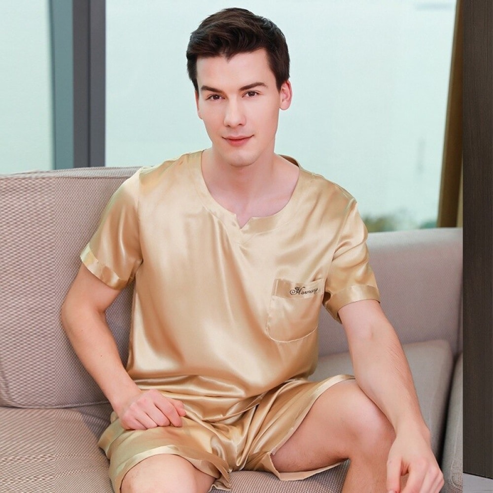 Pyjama doré en satin pour homme doré porté par un homme qui s'assoit sur un canapé dans une maison