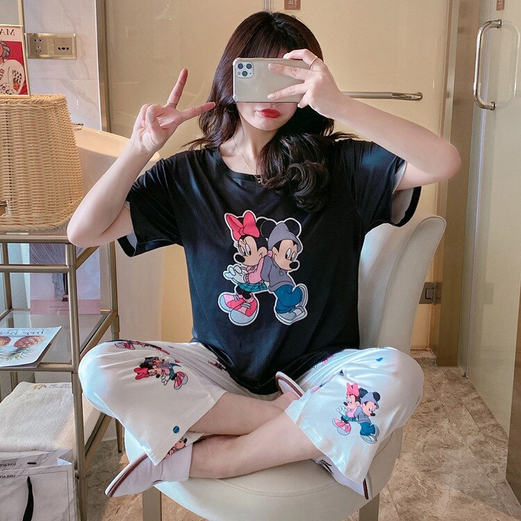 Pyjama deux pièces noir à motif Minnie et Mickey portée par une femme assise sur une chaise à la mode dans une maison