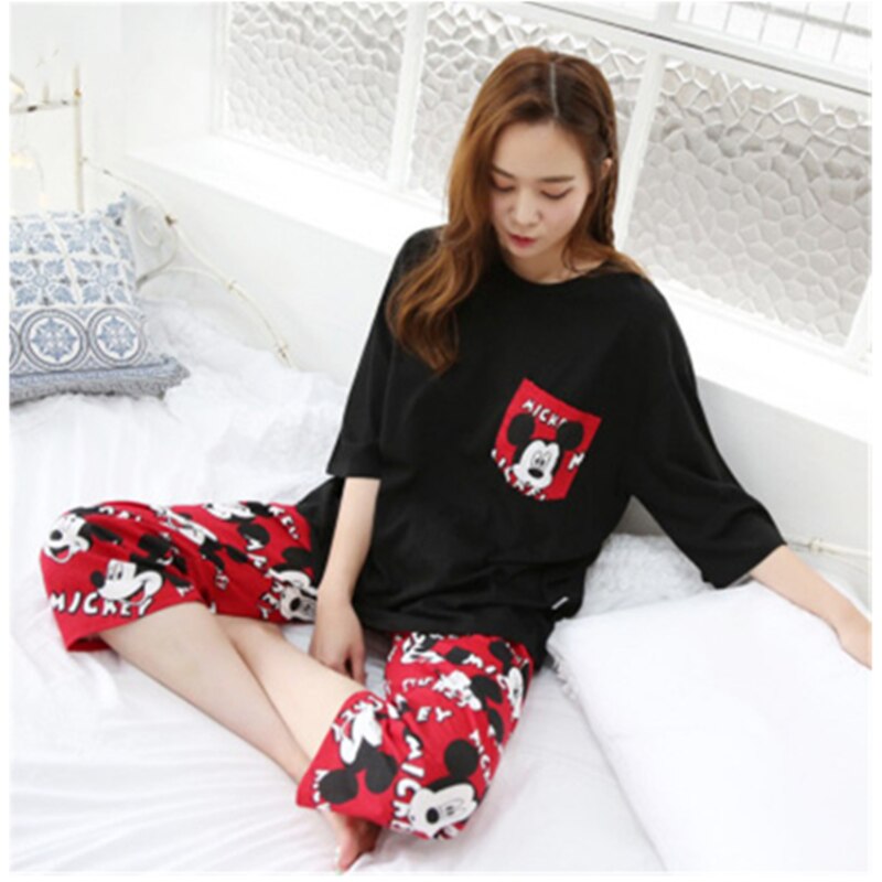 Pyjama deux pièces manches courtes motif Mickey noir et rouge portée par une femme assise sur un tapis