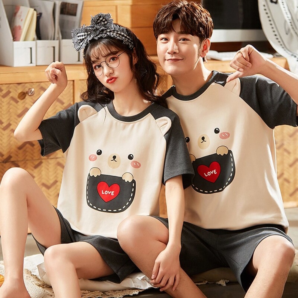 Pyjama deux pièces en coton t-shirt et short motif ours porté par une couple assise sur une chaise dans une maison