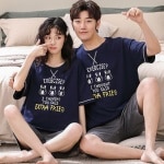 Pyjama deux pièces en coton t-shirt et short motif lapin porté par une couple assise sur un tapis devant un canapé dans une maison