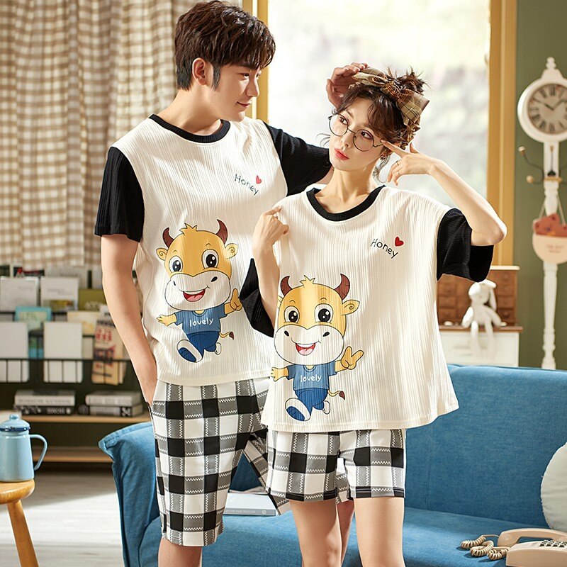 Pyjama t-shirt motif taureau et short carreaux en coton portés par un couple devant une chaise dans une maison