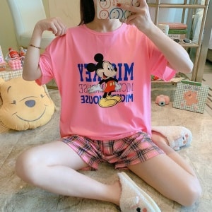 Pyjama t-shirt et short rose motif Mickey carreau assise porté par une femme dans une maison
