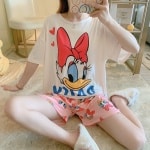 Pyjama t-shirt et short motif Daisy porté par une femme assise sur un tapis dans une maison