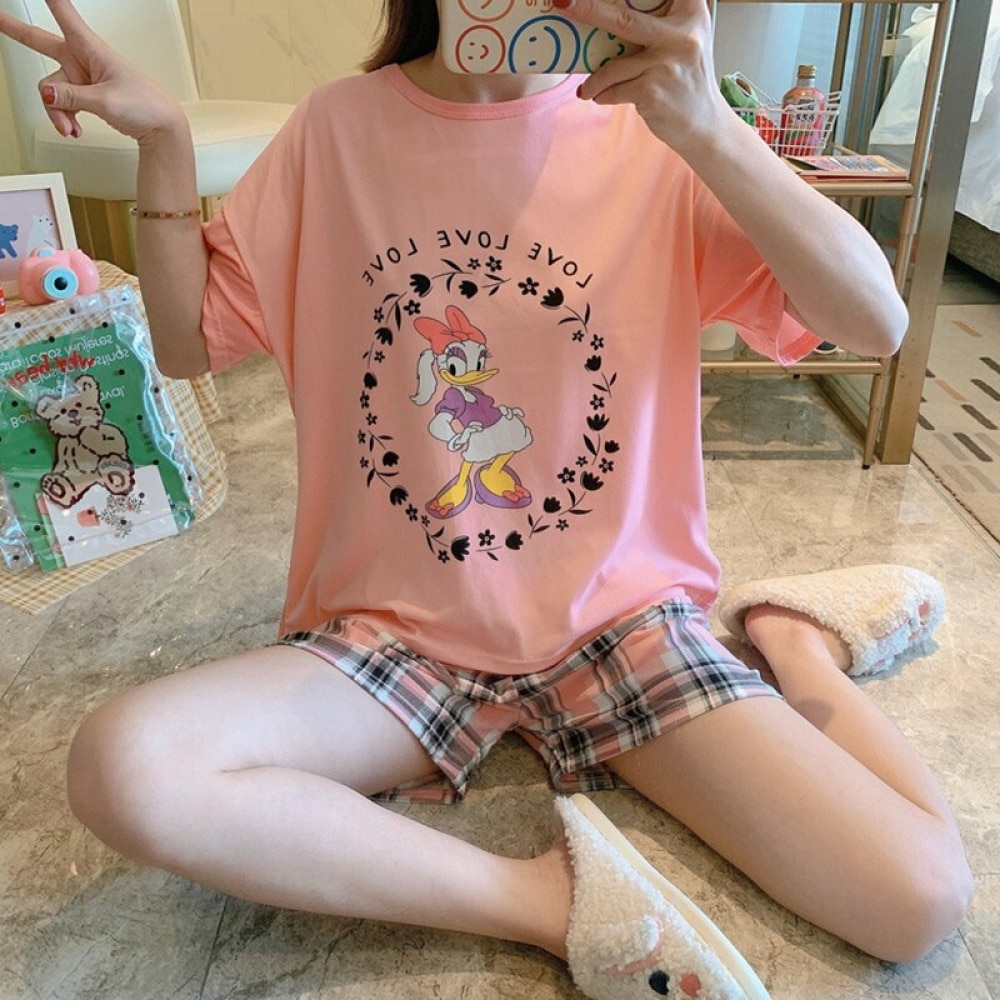 Pyjama deux pièces t-shirt et short motif Daisy porté par une femme assise qui prend une photo