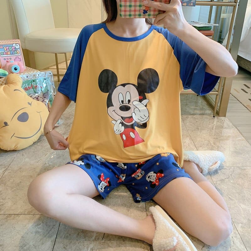 Pyjama deux pièces t-shirt et short motif Mickey portée par une femme assise sur qui prend une photo dans une maison