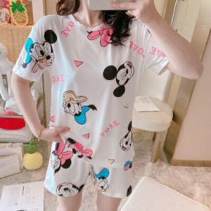 Pyjama en soie à manches courtes motif Mickey et Donald porté par une femme qui prend une photo dans une maison