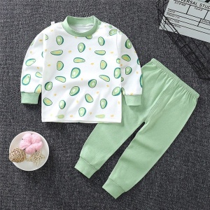 Pyjama pour petit garçon en coton motif avocat avec un pantalon vert uni à la mode sur un tapis dans une maison
