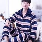 Pyjama ligné molletonné pour homme rayure porté par un homme devant un canapé dans une maison
