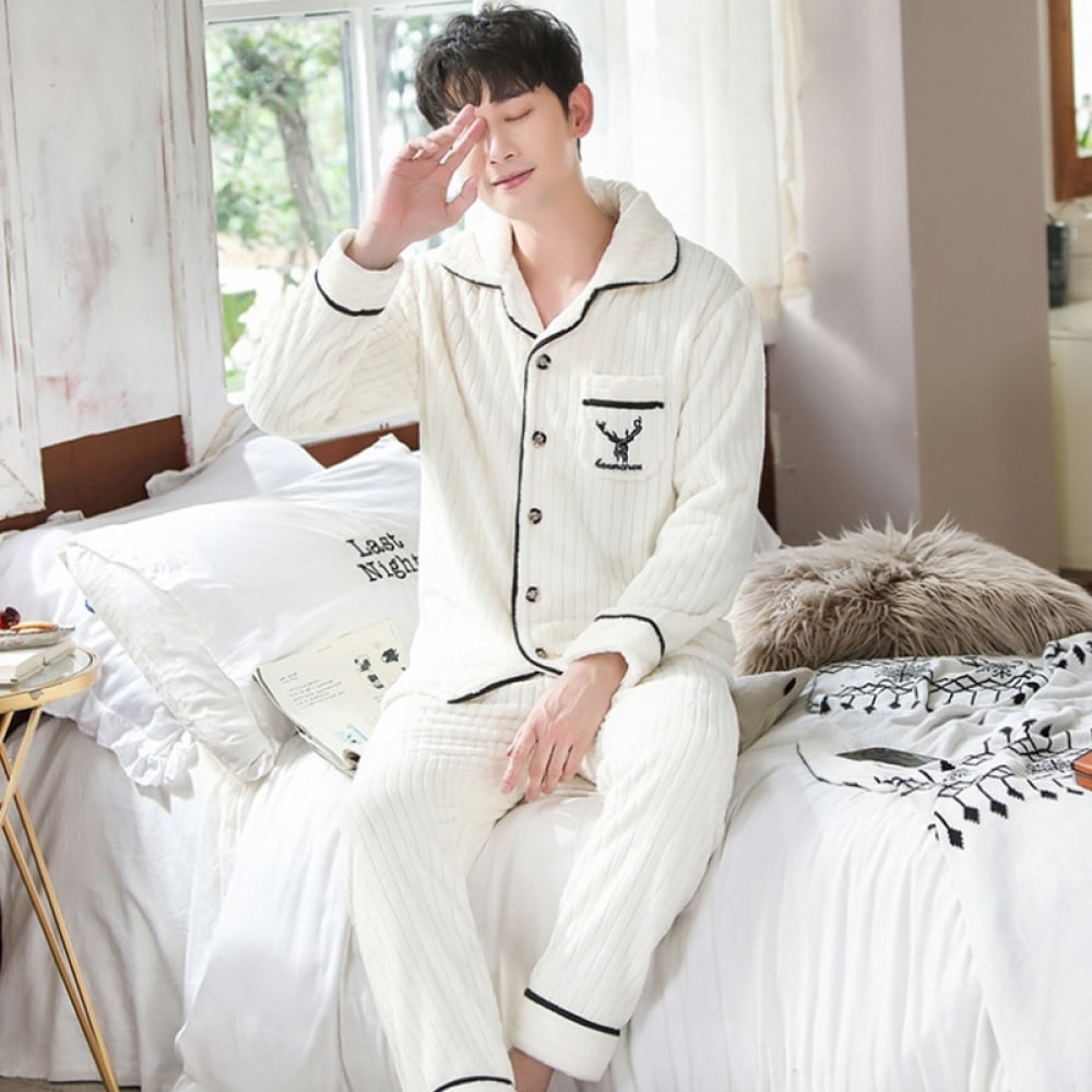 Pyjama en polyester pour homme motif ligné porté par un homme qui s'assoit sur un lit dans une maison