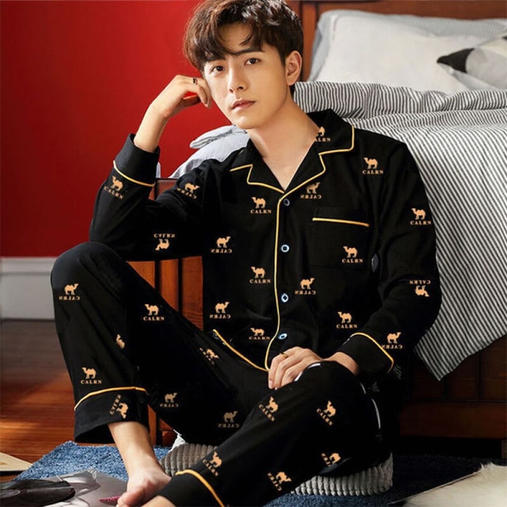 Pyjama chameaux en coton porté par un homme assise sur un tapis devant un lit dans une maison