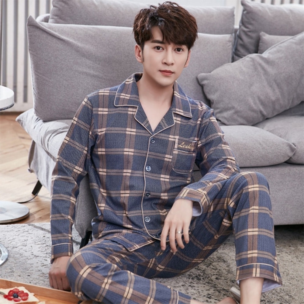 Pyjama double carreaux pour homme porté par un homme assise sur un tapis devant un canapé dans une maison