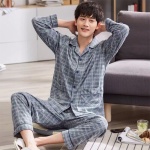 Pyjama pour homme en coton rayures gris porté par un homme assis sur un tapis devant un canapé dans une maison
