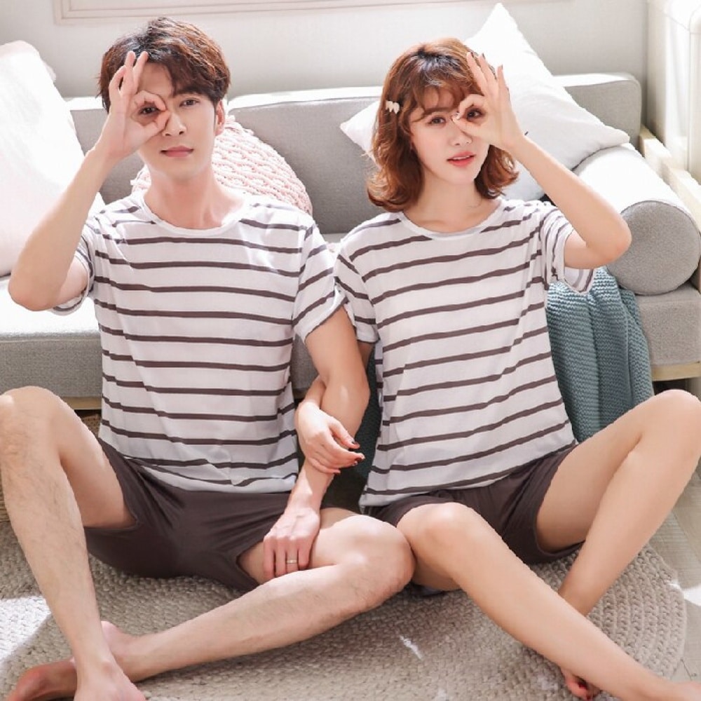 Vêtements de nuit pour couple modèle ligné portés par une couple assise sur un tapis dans une maison