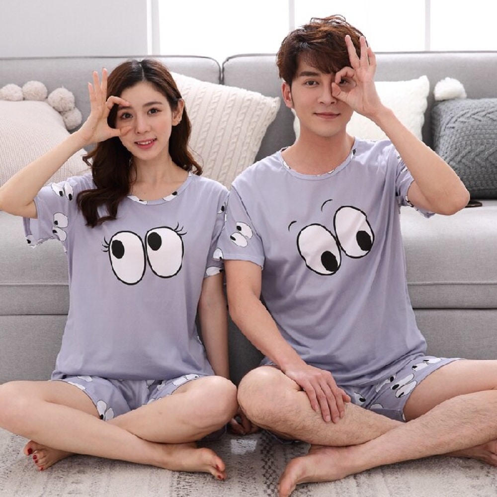 Ensemble pyjama motif yeux pour couple porté par une couple assise sur un tapis dans une maison