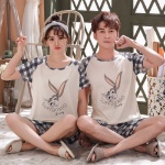 Pyjama à carreaux motif lapin pour couple portés par une couple assise sur un tapis dans une maison