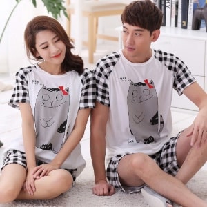 Pyjama pour couple motif chat en coton à la mode, porté par un couple dans une maison