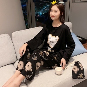 Ensemble pyjama noir avec Winnie l'ourson pour femme à la mode porté par une femme assise sur un canapé dans une maison