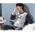 Pyjama avec motif Panda pour homme porté par un homme qui s'assoit sur un canapé dans une maison