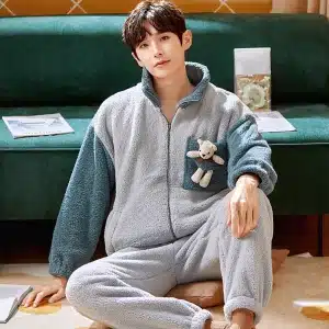 Pyjama hiver avec ourson pour homme porté par un homme qui s'assoit sur un tapis devant un canapé dans une maison