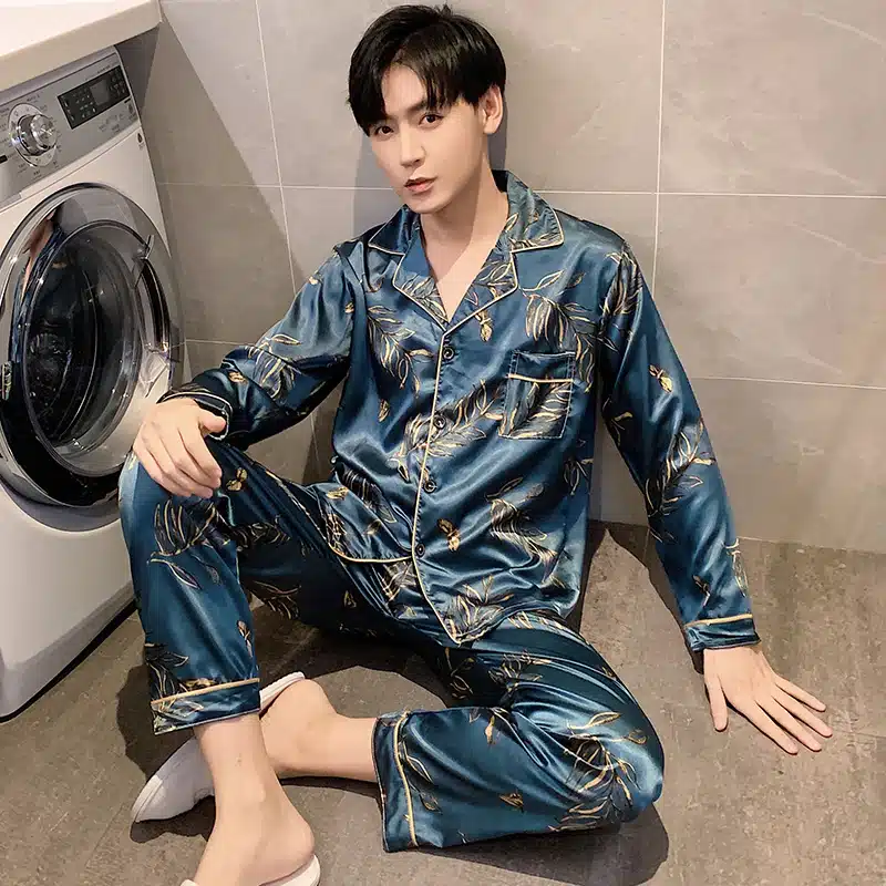 Pyjama satiné bleuté pour homme porté par un homme qui s'assoit devant une machine à laver dans une maison