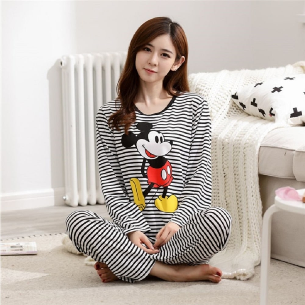 Pyjama rayé Mickey pour femmes porté par une femme assise devant un lit dans une maison