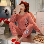 Pyjama rose Mickey pour femme porté par une femme qui porte une serre tête rouge dans une maison à la mode