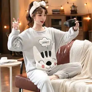 Pyjama avec tête de chat en polaire pour couple très confortable à la mode portée par une femme assise sur une chaise dans une maison