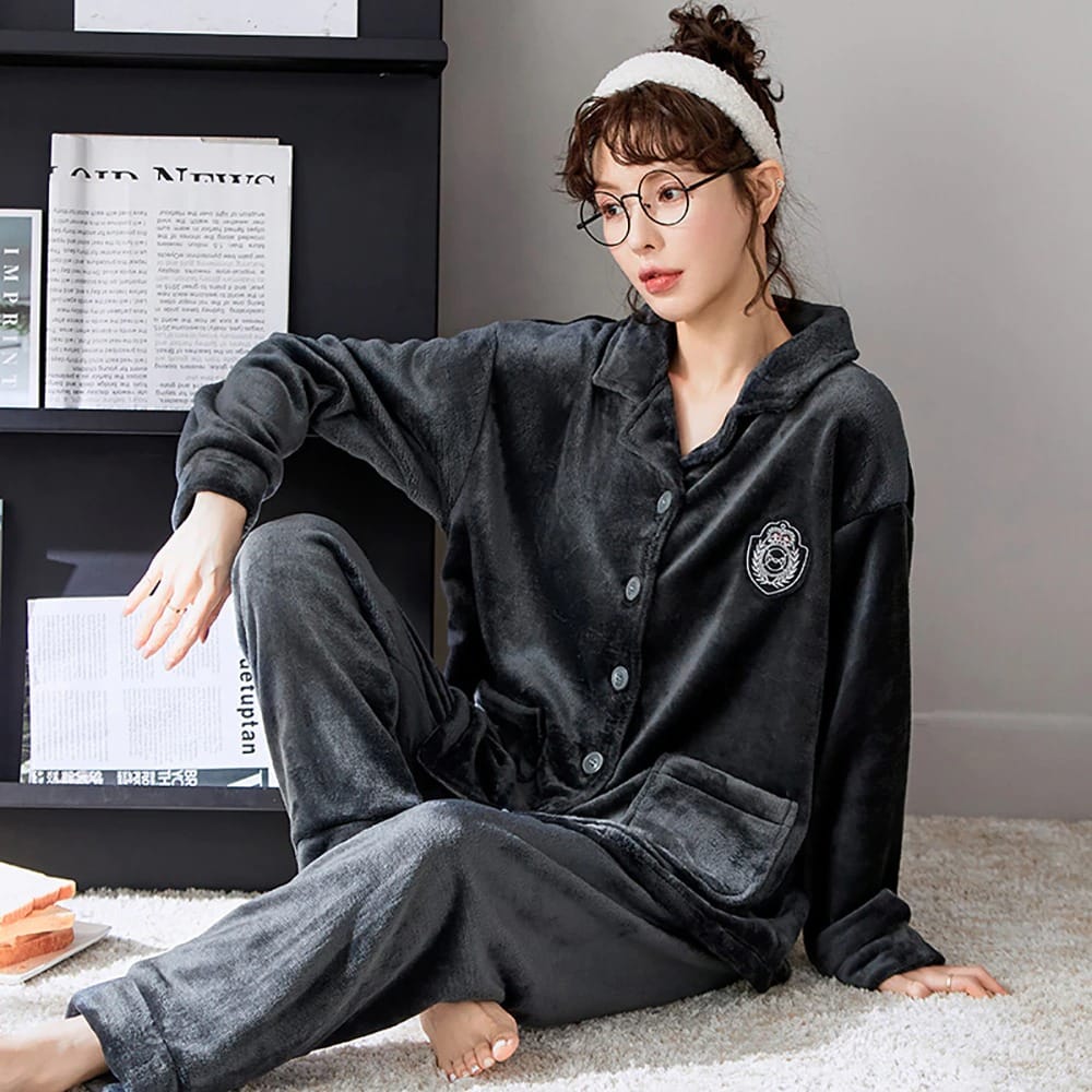 Pyjama uni en polaire avec col pour couple gris porté par une femme assise sur un tapis dans une maison