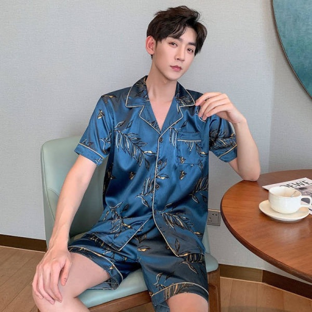 Pyjama d'été en soie bleu pour homme porté par un homme assise sur une chaise dans une maison