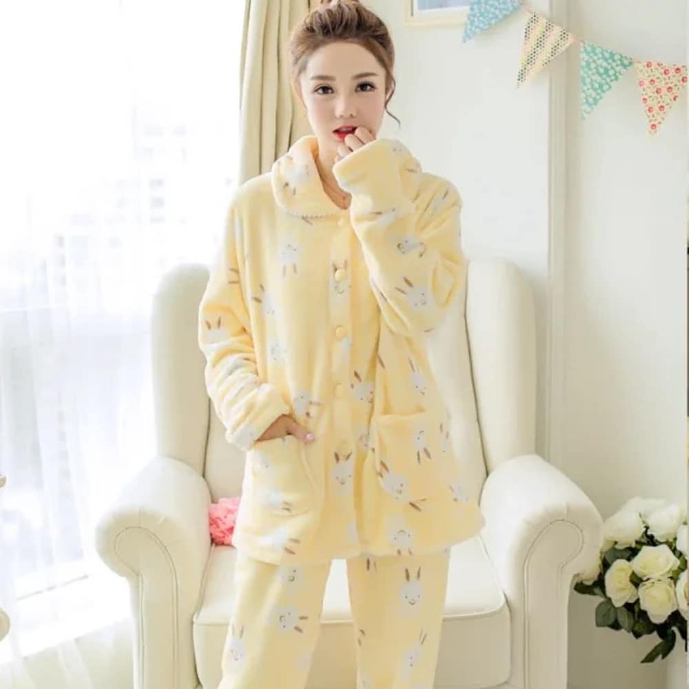 Pyjama d’hiver manches longues motif jaune lapin très confortable porté par une femme devant une chaise dans une maison