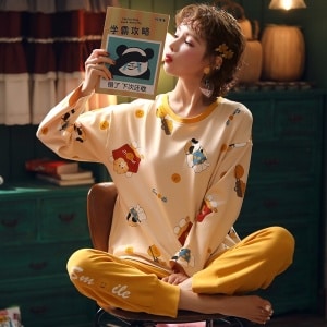 Pyjama automne avec pull-over et pantalon jaune pour femmes portée par une femme qui lisent une livre assise sur une chaise