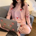 Pyjama automne à manches longues avec imprimé cochons porté par une femme assise sur une chaise dans une maison