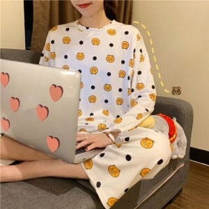 Pyjama automne à manches longues avec imprimé orange porté par une femme assise sur un canapé dans une maison