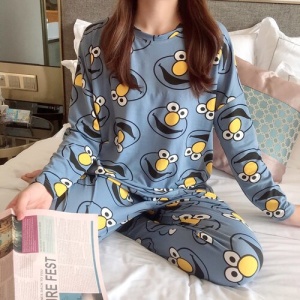 Pyjama automne à manches longues avec imprimé Elmo porté par une femme assise sur un lit dans une maison