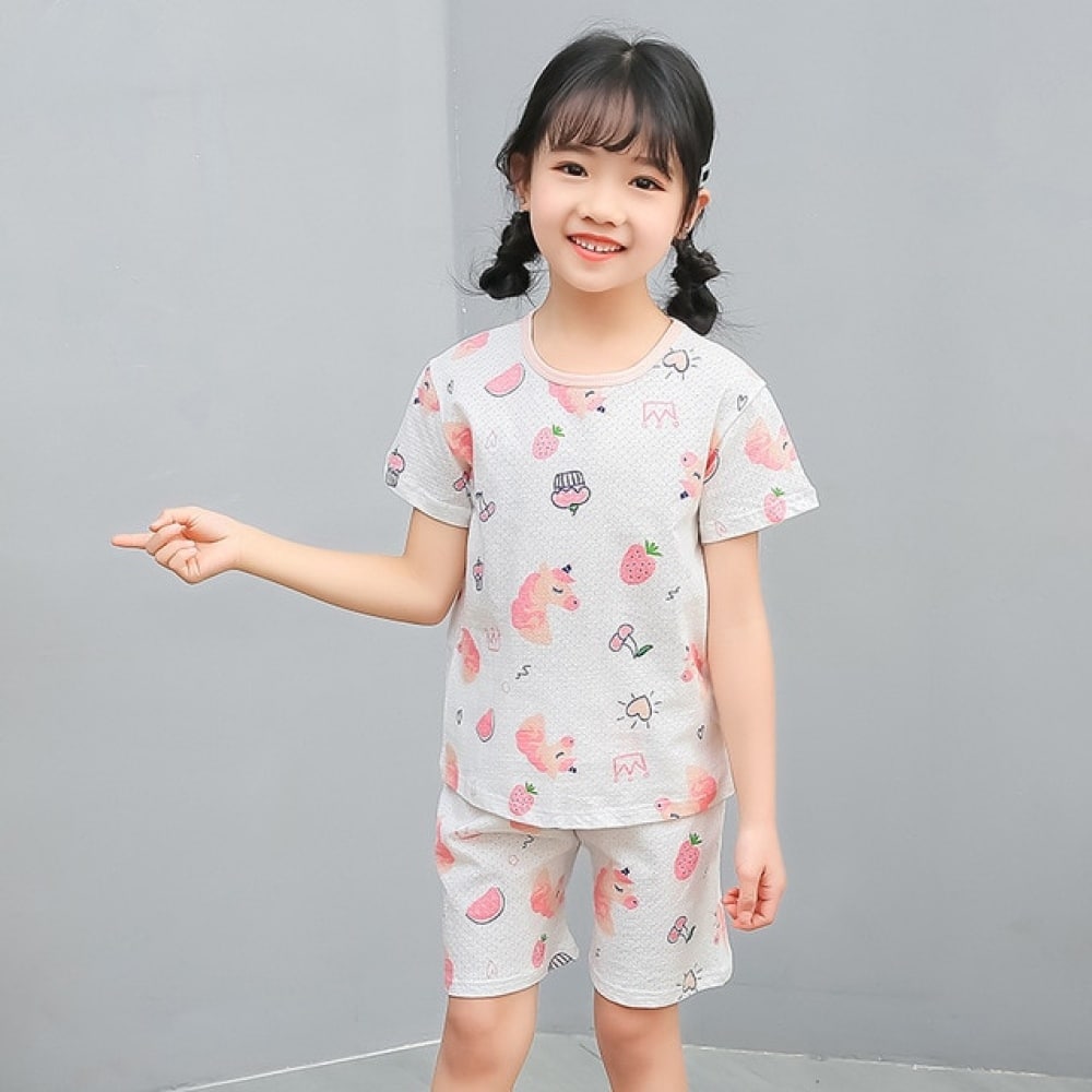 Pyjama blanc deux pièces à motif dessin animé pour petite fille avec une petite fille qui porte le pyjama et un fond gris