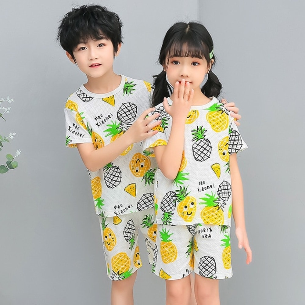 Pyjama blanc deux pièces à motif ananas avec deux enfants qui porte le pyjama et un fond gris