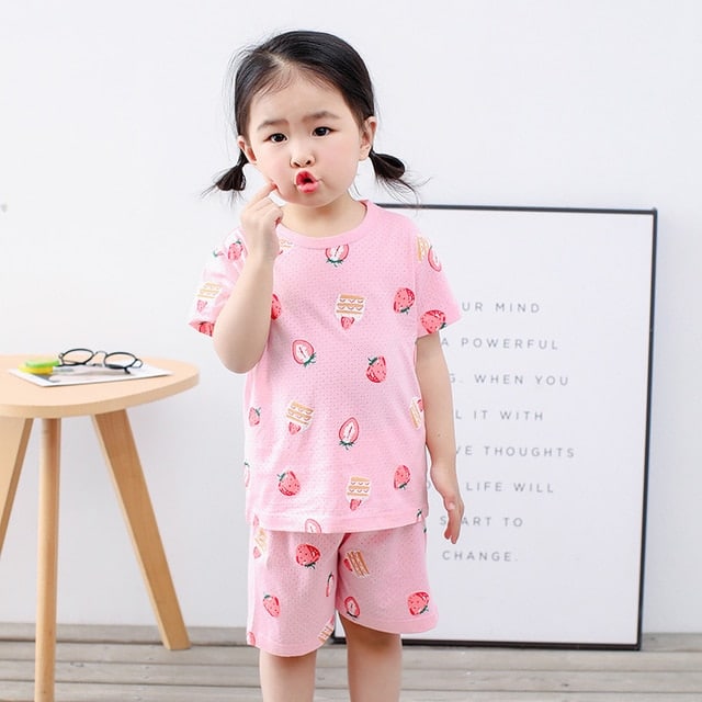 Pyjama rose deux pièces à motif fraise pour petite fille avec une petite fille toute mignonne qui porte le pyjama