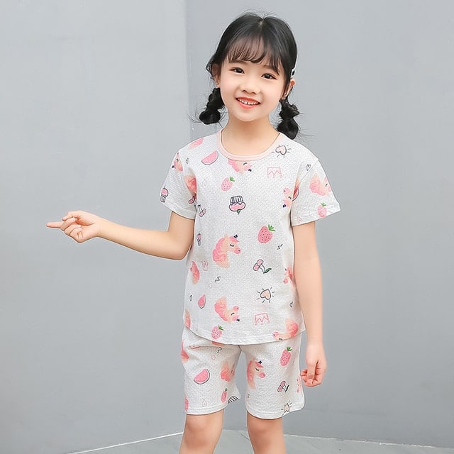 Pyjama blanc deux pièces à motif dessin animé pour petite fille avec une petite fille qui porte le pyjama et un fond gris