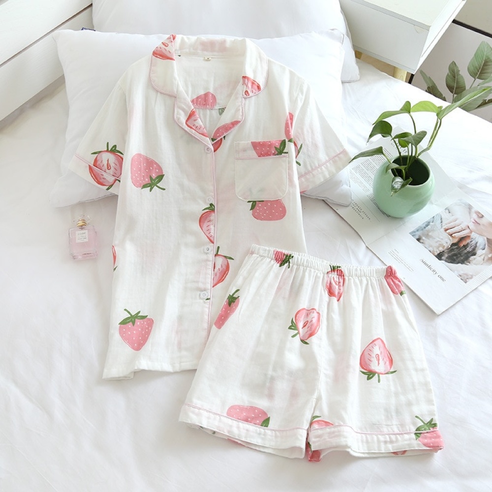 Pyjama d'été manches courtes avec imprimé fraises pour femmes sur un lit avec un petit vase et une fleur à l'intérieur dans une maison