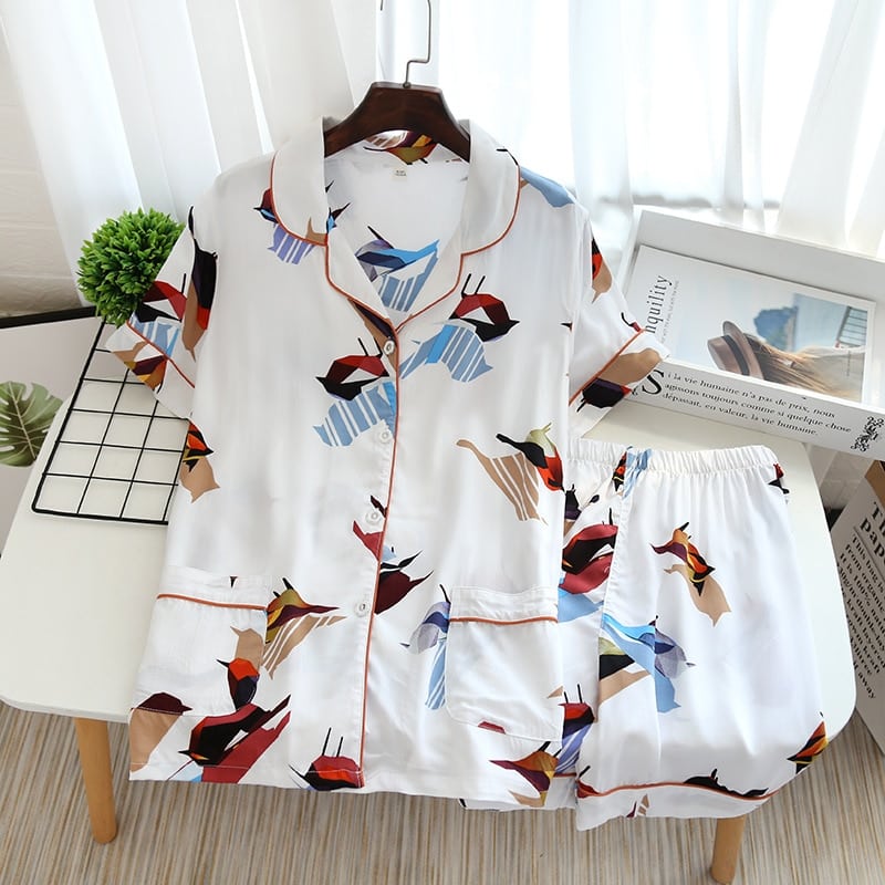 Pyjama d'été blanc manches courtes avec imprimé oiseaux pour femmes sur une table avec un magazine comme décoration