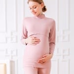 Pyjama de grossesse en coton rose en deux pièce est porté par une femme blonde enceinte
