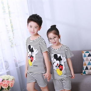 Pyjama d'été à rayure noir et blanc avec imprimé Mickey Mousse pour enfant porté par un petiot garçon et une petite fille devant une chaise dans une maison