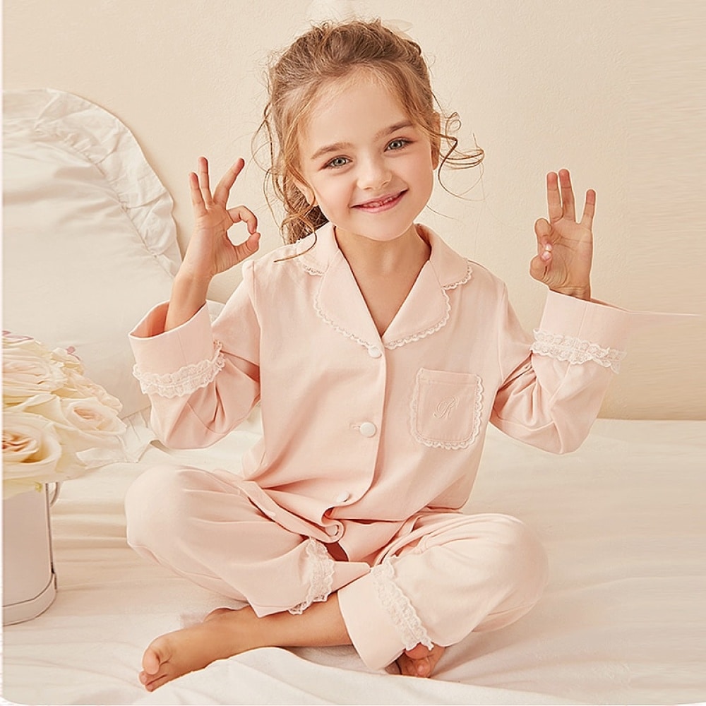 Pyjama deux pièces en dentelle pour "faire comme Maman" avec une petite fille qui porte le pyjama avec un fond un lit d'enfant blanc et un fond rose