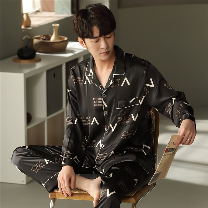 Pyjama noir en coton à manches longues avec col rabattu pour homme porté par un homme assise sur une chaise dans une maison