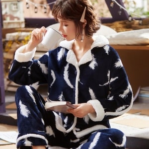 Pyjama polaire épais composé d'un pantalon ainsi que d'un chemisier épais. La couleur du pyajama est bleue. Les motifs sur le pyjama sont des plumes blanches.